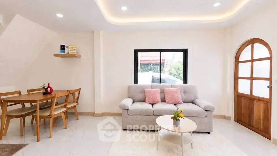 Charming living room with cozy sofa, elegant dining area, and natural light from large window.