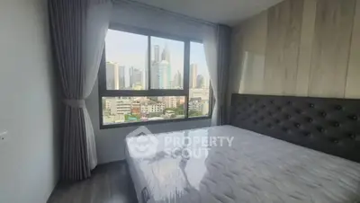 Modern bedroom with city view, featuring large window and stylish decor.