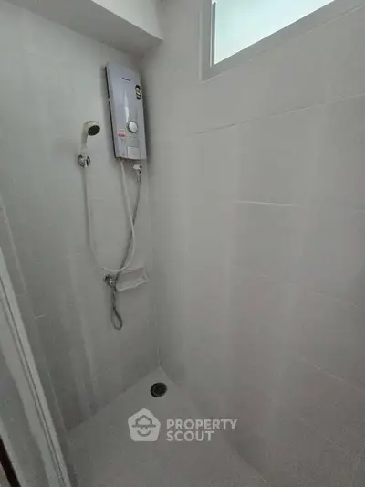 Modern bathroom with sleek shower and water heater in minimalist design.