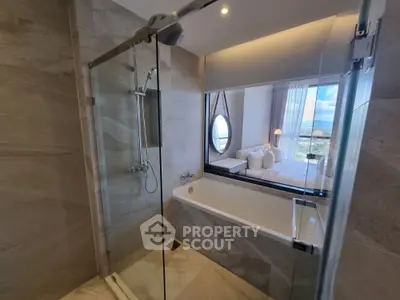 Luxurious bathroom with modern shower and bathtub, offering a glimpse into a cozy bedroom with scenic views.