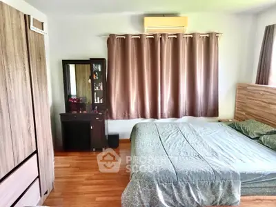 Cozy bedroom with wooden flooring, elegant curtains, and stylish furniture for a comfortable living experience.
