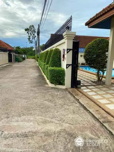 Charming residential entrance with lush greenery and poolside view