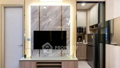 Modern living room with sleek TV setup and adjacent compact kitchen area.