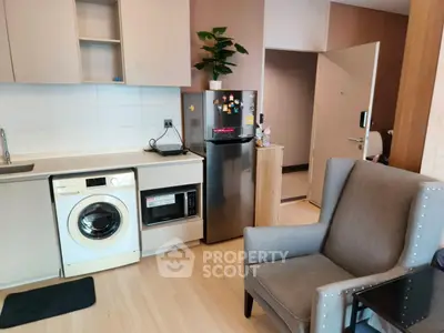 Modern kitchen with washing machine, microwave, and fridge in cozy apartment