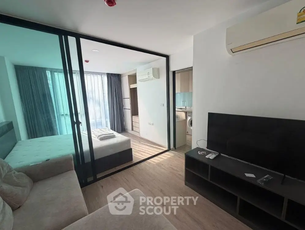 Modern studio apartment with glass partition, cozy living area, and natural light.