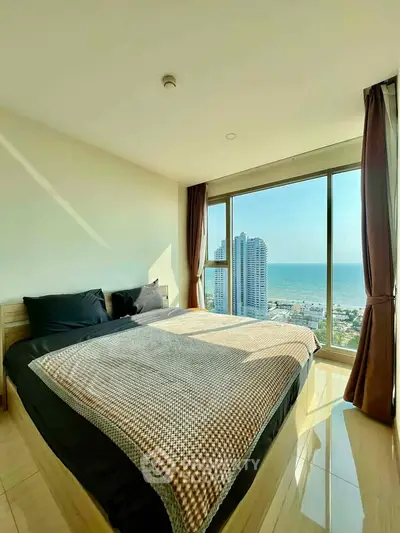 Luxurious bedroom with stunning ocean view and floor-to-ceiling windows in high-rise apartment.