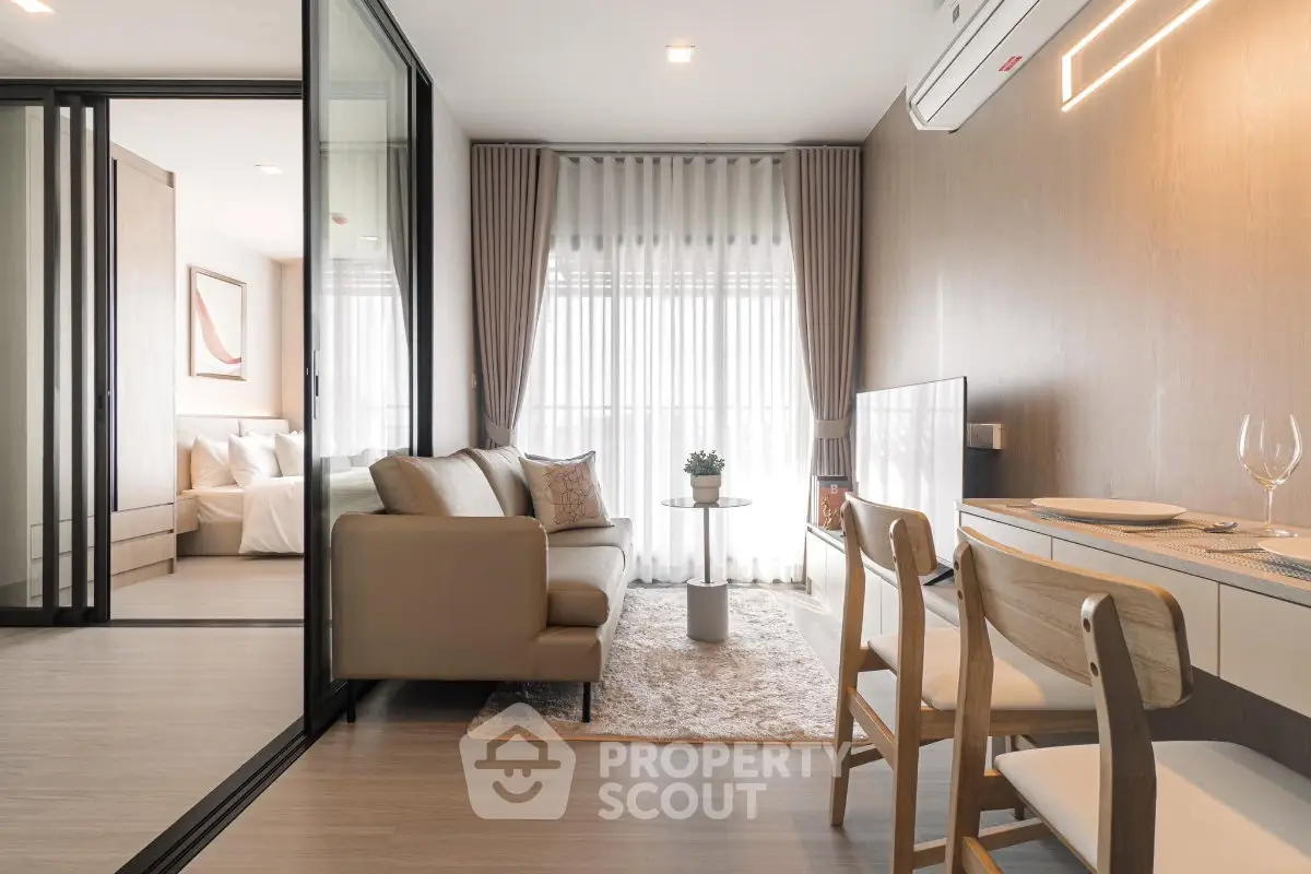 Modern open-plan living room with dining area and cozy bedroom in a stylish apartment.