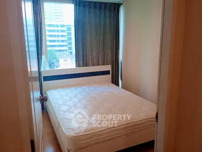 Cozy bedroom with large window offering city views, featuring a comfortable bed and modern decor.