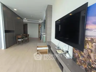 Modern living room with large TV and dining area, featuring sleek design and open layout.