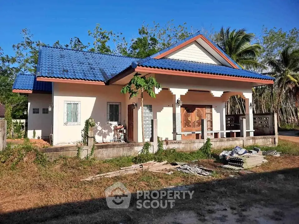 Charming single-story house with blue roof and spacious front porch in a serene rural setting.
