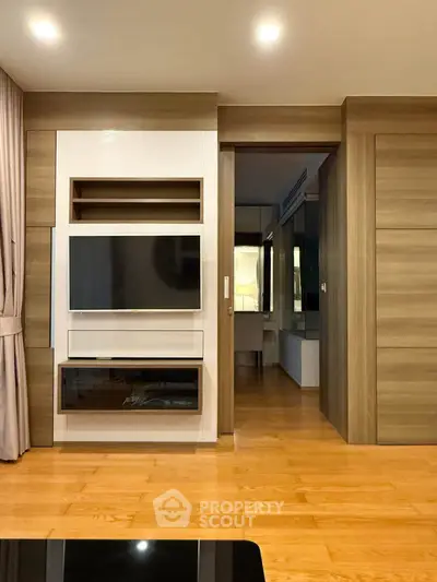 Modern living room with sleek wooden flooring and built-in TV unit