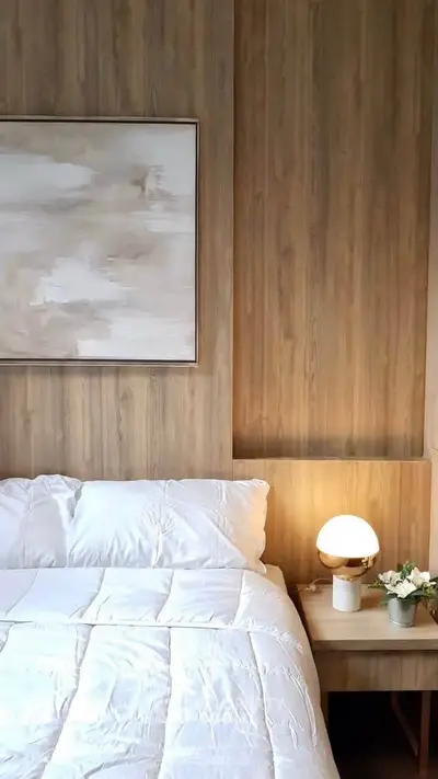 Elegant bedroom with modern decor and cozy lighting, featuring a stylish wooden accent wall and contemporary artwork.