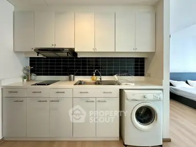 Modern kitchen with sleek cabinetry and washing machine in stylish apartment.