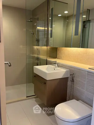 Modern bathroom with glass shower and sleek fixtures in contemporary apartment.