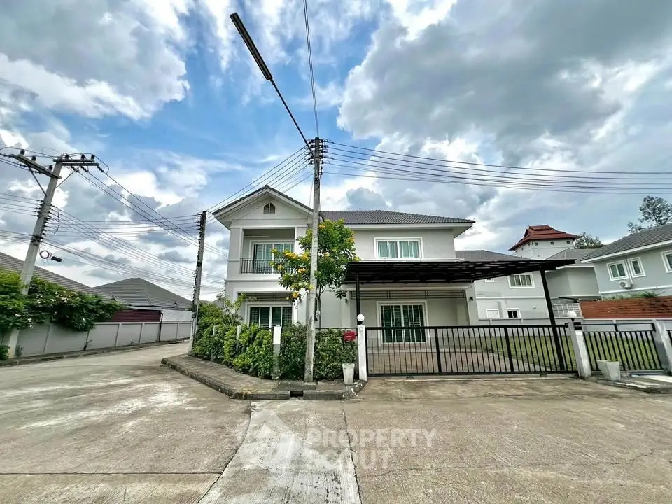 Charming two-story house with a spacious driveway and lush greenery under a cloudy sky.