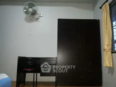 Minimalist bedroom with dark furniture and wall-mounted fan