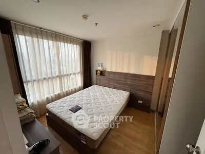 Cozy bedroom with large window and natural light, featuring a comfortable bed and modern decor.