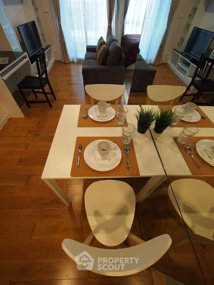 Modern living room with dining area, wooden flooring, and stylish decor in a cozy apartment setting.