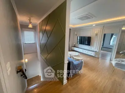 Modern living room with stylish decor and staircase, featuring elegant lighting and wood flooring.