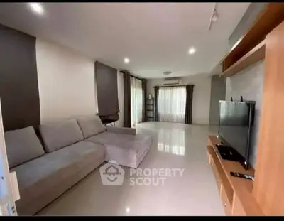 Spacious modern living room with large sofa and flat-screen TV, ideal for relaxation and entertainment.
