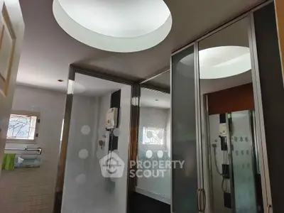 Modern bathroom with frosted glass shower doors and circular skylight