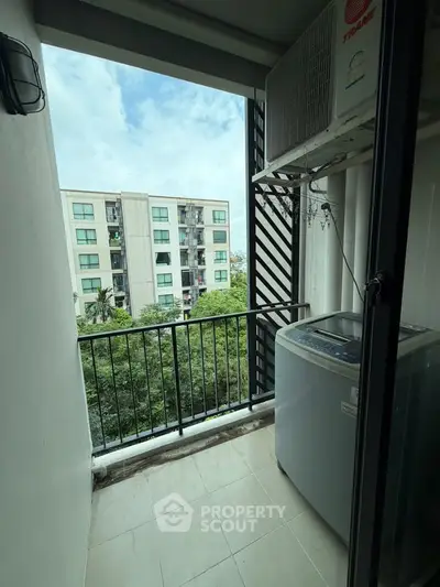 Charming balcony with laundry area and scenic view of residential building and greenery.