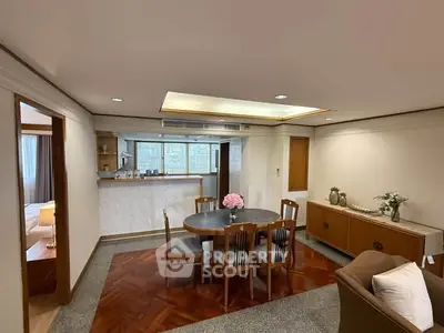 Spacious dining area with elegant wooden flooring and open kitchen layout in modern apartment.