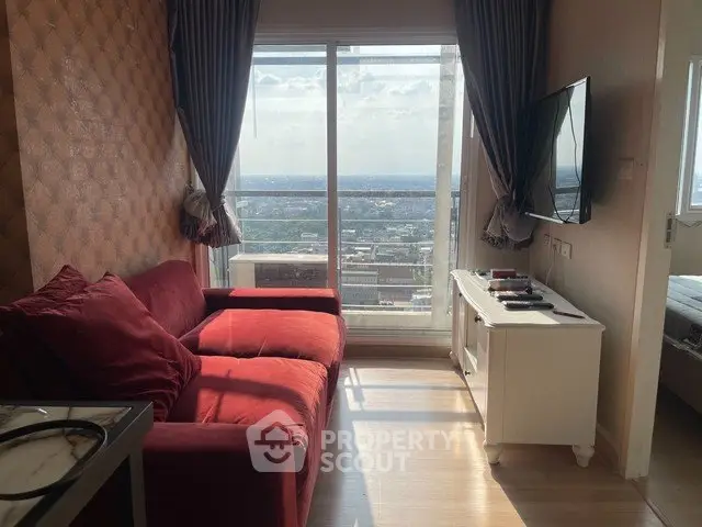 Cozy living room with red sofa and stunning city view through large window.