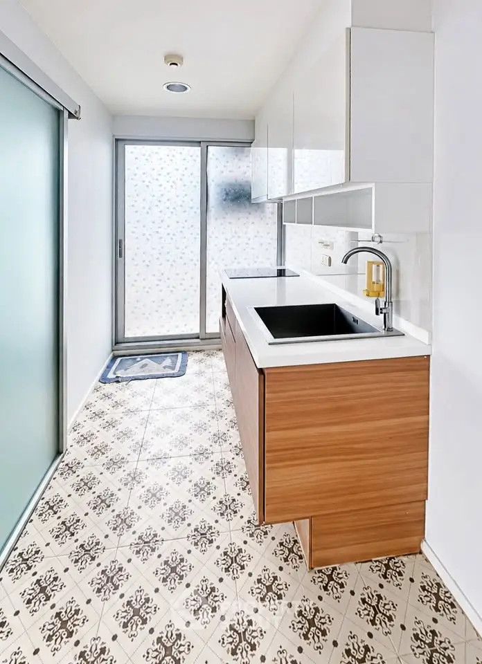 Modern kitchen with sleek cabinetry and patterned floor tiles, featuring a minimalist design and ample natural light.