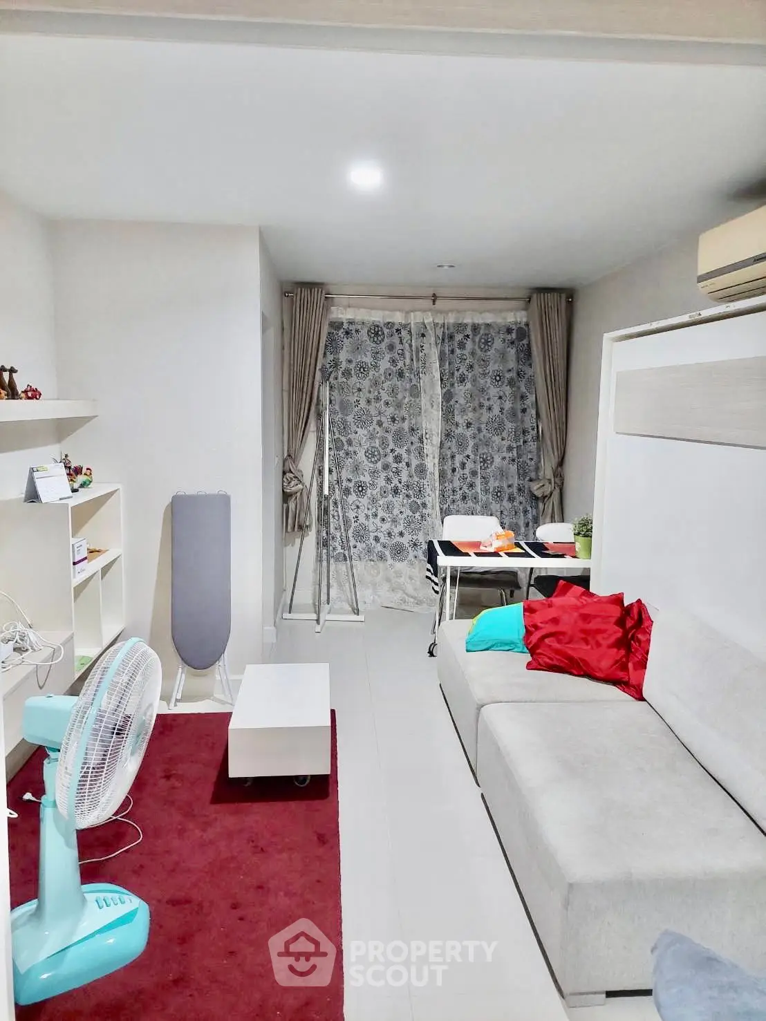 Modern living room with cozy sofa, red carpet, and stylish decor in a bright apartment.