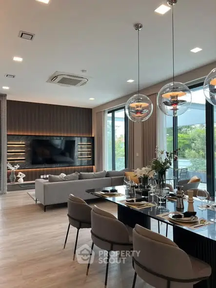 Luxurious modern living room with elegant dining area and large windows offering a serene garden view.