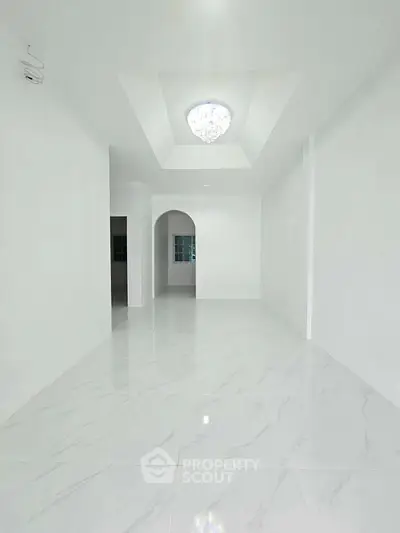 Spacious white interior with elegant ceiling light and glossy marble flooring.