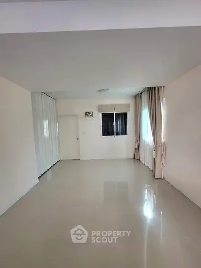 Spacious empty room with glossy tiled floor and large window