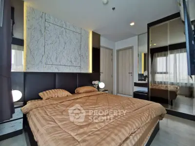 Luxurious bedroom with elegant marble accent wall and mirrored wardrobe in modern apartment.