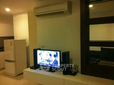 Modern living room with air conditioning and entertainment setup, featuring a sleek TV and refrigerator.