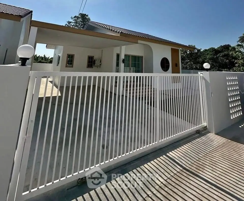 Modern single-story house with gated entrance and spacious driveway.