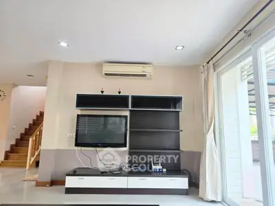 Modern living room with sleek TV unit and air conditioning, featuring large windows for natural light.