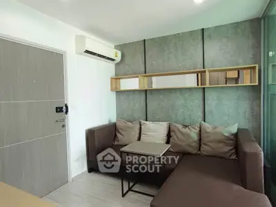 Modern living room with stylish sectional sofa and wall-mounted air conditioner in a cozy apartment.