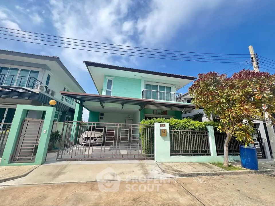 Charming two-story house with gated driveway and lush greenery in a serene neighborhood.