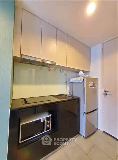 Modern compact kitchen with sleek cabinetry and built-in appliances in urban apartment.
