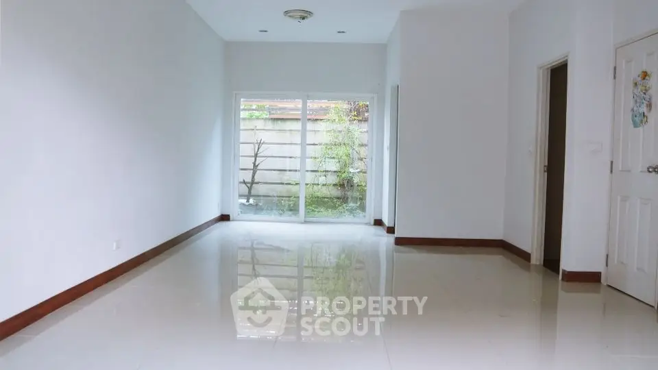 Spacious empty room with large window and glossy tiled floor