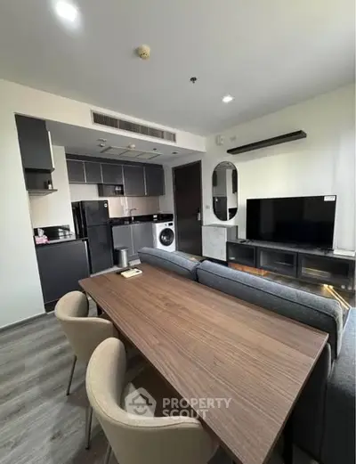 Modern open-layout living room with kitchen, featuring sleek furniture and appliances.