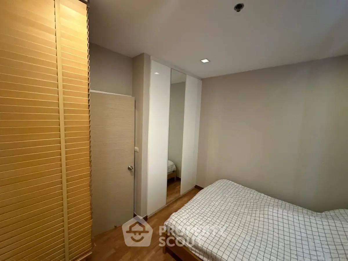 Cozy bedroom with wooden flooring and mirrored wardrobe