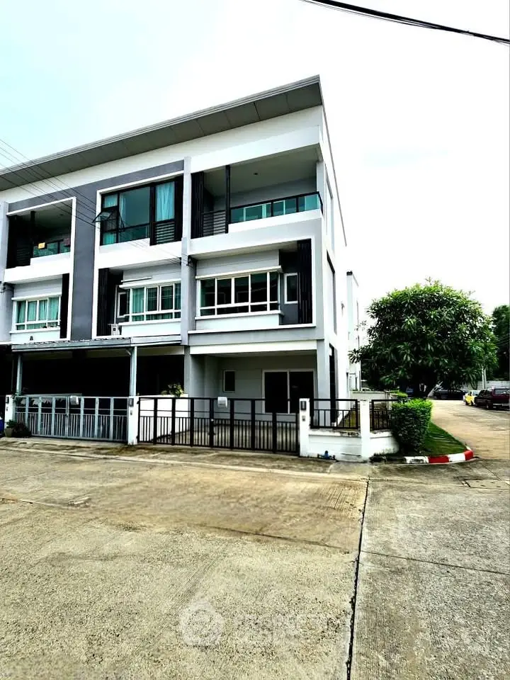 Modern three-story townhouse with sleek design and spacious driveway in a serene neighborhood.