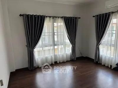 Spacious corner unit with elegant curtains and wooden flooring, ideal for a cozy living room setup.