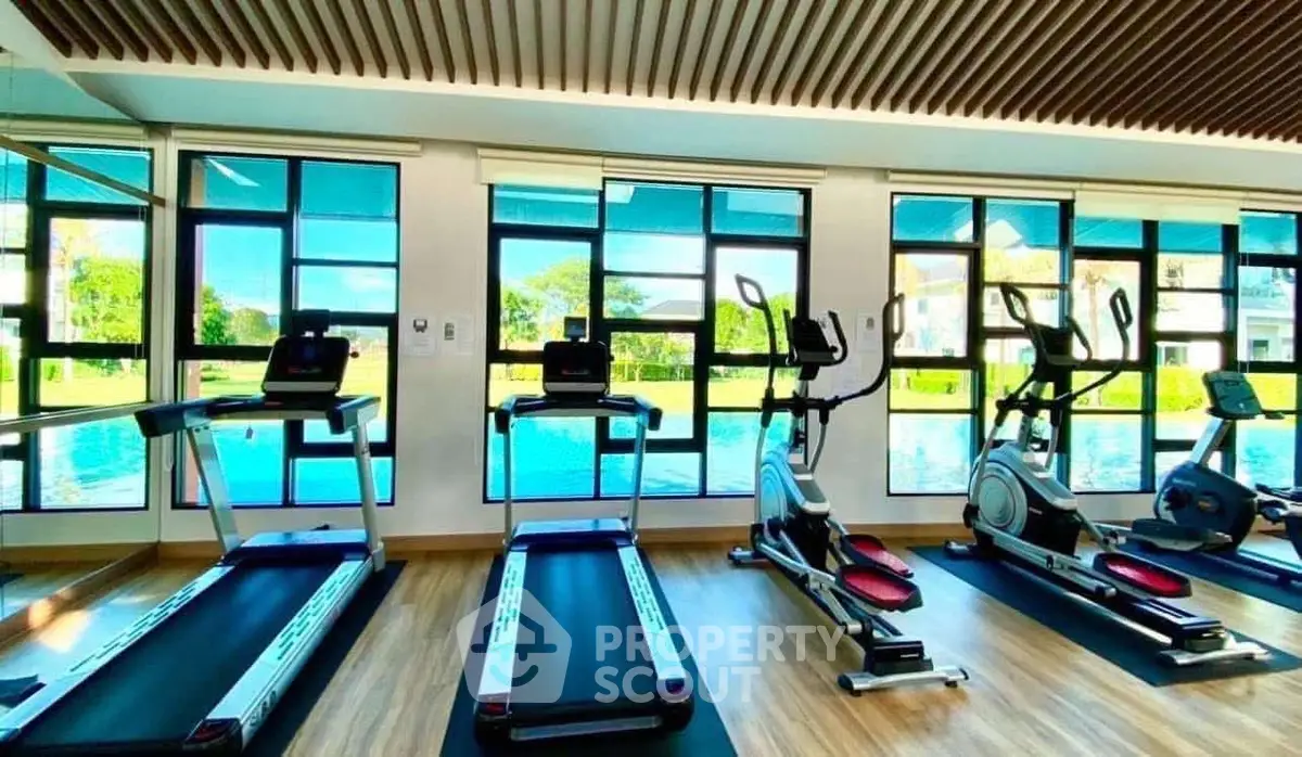 Modern gym with pool view, featuring state-of-the-art exercise equipment and large windows.