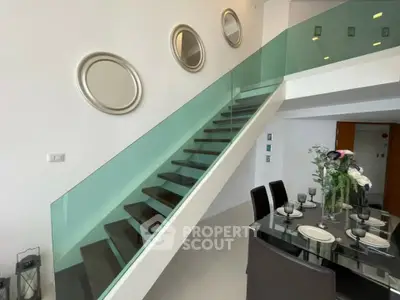 Modern duplex interior with glass staircase and elegant dining area