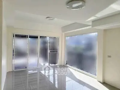 Bright and spacious room with large frosted windows and glossy tiled floor, perfect for modern living.