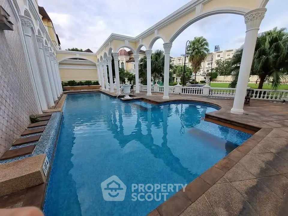 Luxurious outdoor pool with elegant arches and lush greenery, perfect for relaxation and leisure.