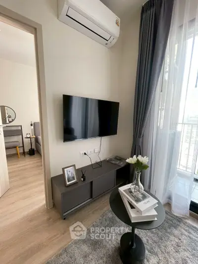 Modern living room with sleek TV setup and stylish decor, featuring a glimpse of a cozy bedroom.